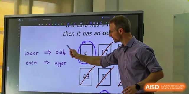 A foreign teacher from The Affiliated High School of Peking University's Dalton Academy using an interactive whiteboard to teach a lesson on concepts like "odd" and "even" to students.