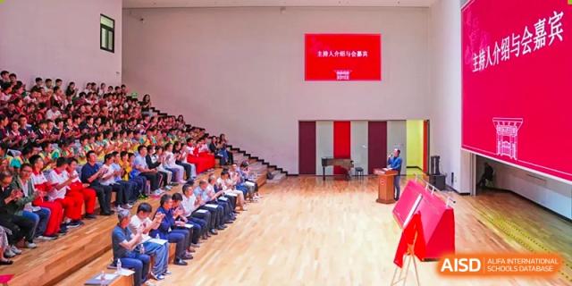 Students from The Affiliated High School of Peking University's Dalton Academy seated in neat rows in a large, modern auditorium or hall during an assembly or lecture.