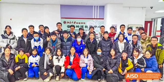 A large group of students and staff from The Affiliated High School of Peking University's Dalton Academy gathered closely for a group photo, many wearing blue and white jackets.