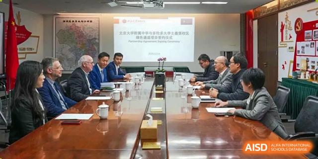 A group of administrators and staff from The Affiliated High School of Peking University's Dalton Academy attending a formal meeting with a presentation visible on a screen.