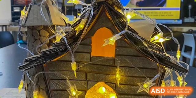 A close-up view of a small, decorative wooden structure resembling a house or monument, used as decor at an event for The Affiliated High School of Peking University's Dalton Academy.