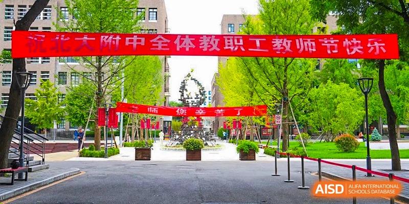 A view of the school entrance or campus pathway with red banners announcing a faculty and staff event at The Affiliated High School of Peking University's Dalton Academy.