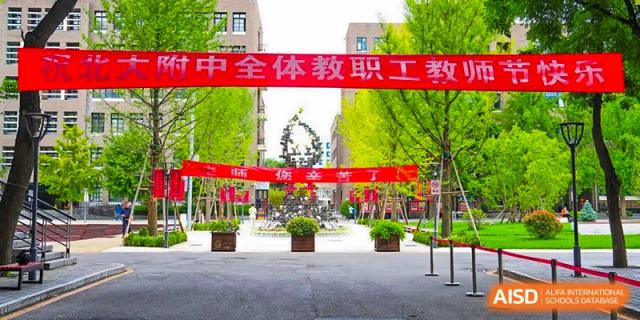 A view of the school entrance or campus pathway with red banners announcing a faculty and staff event at The Affiliated High School of Peking University's Dalton Academy.