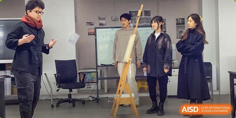 Two students standing next to an easel and a canvas, posing in an art studio or classroom at The Affiliated High School of Peking University's Dalton Academy.