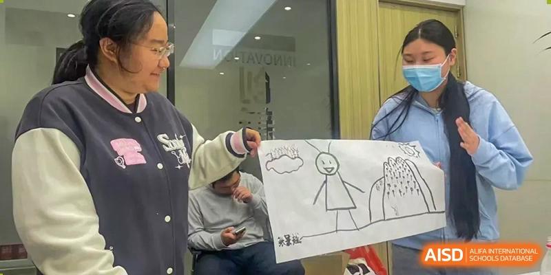 A student presenting a simple, quick drawing of stick figures to peers during a fun creative challenge or activity at The Affiliated High School of Peking University's Dalton Academy.