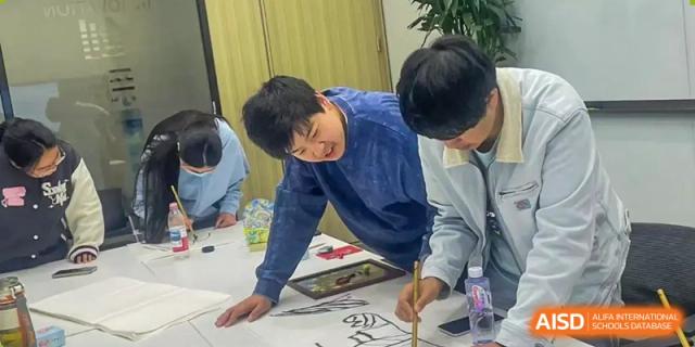 A student intently focused on creating a drawing or piece of artwork on paper with various supplies during a creative class at The Affiliated High School of Peking University's Dalton Academy.