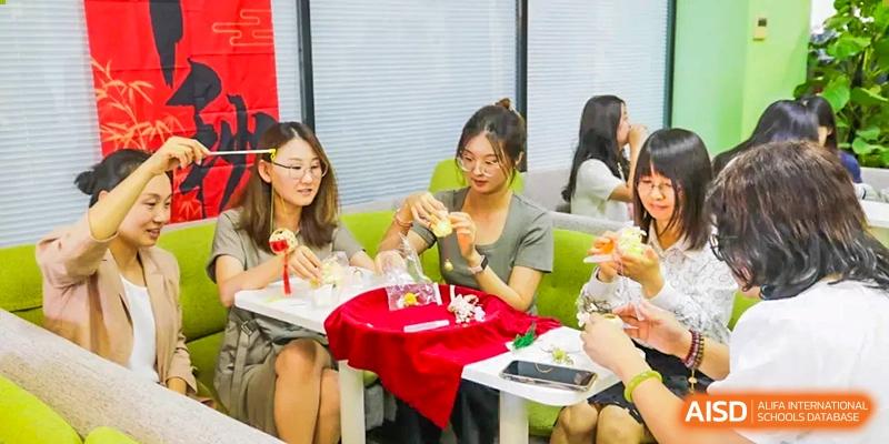 A group of female students participating in a craft or creative activity, handling small decorative objects at a table at The Affiliated High School of Peking University's Dalton Academy.