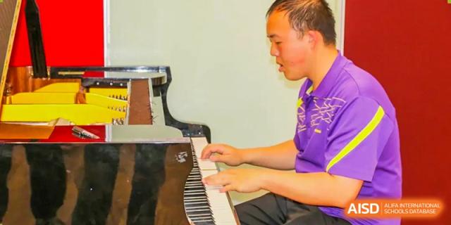 A student from The Affiliated High School of Peking University's Dalton Academy focused on playing a dark upright piano.