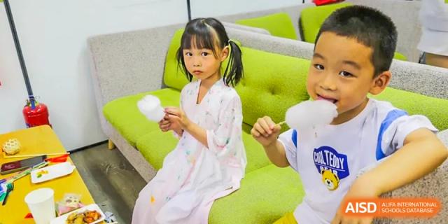 A young girl from the community of The Affiliated High School of Peking University's Dalton Academy standing on a green couch and holding a snack.