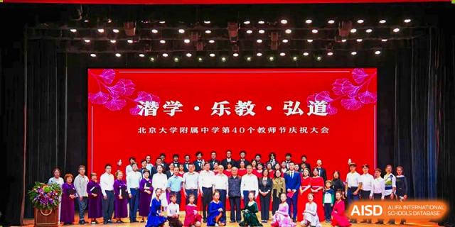 A large group of students and performers from The Affiliated High School of Peking University's Dalton Academy posing on a stage after a performance, under a banner with Chinese text.