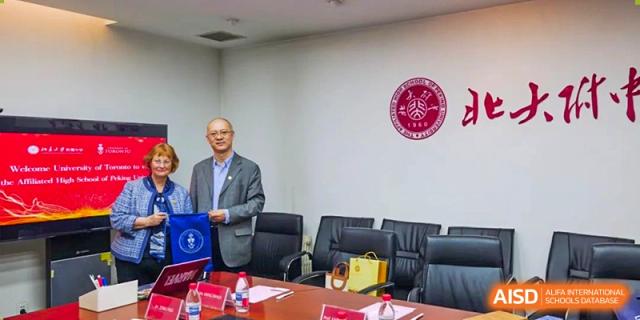 An administrator or guest speaker from The Affiliated High School of Peking University's Dalton Academy giving a presentation or addressing attendees in a professional conference room setting.
