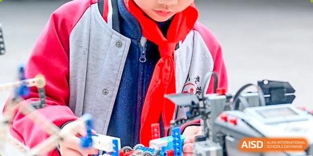 Close-up of a CHONGQING WEIMING SCHOOL student building a robot or mechanical project during a science or technology class.