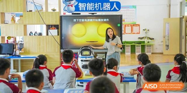 A teacher at CHONGQING WEIMING SCHOOL leads a robotics class, presenting material on a large screen to students.