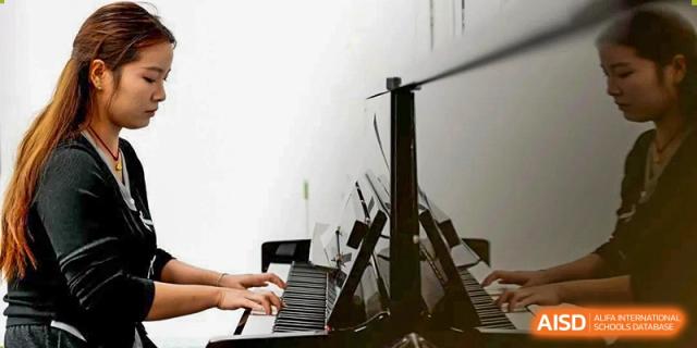 A close-up shot of hands playing a piano or keyboard at CHONGQING WEIMING SCHOOL.