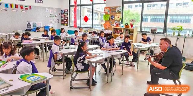 Young students from Cogdel Cranleigh School Changsha seated at long tables and focusing on their work in a brightly lit classroom.