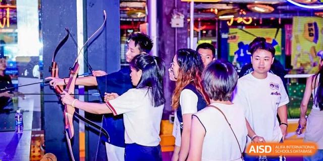 A group of Cogdel Cranleigh School Changsha students socializing or engaging in a discussion during a lively indoor school event.
