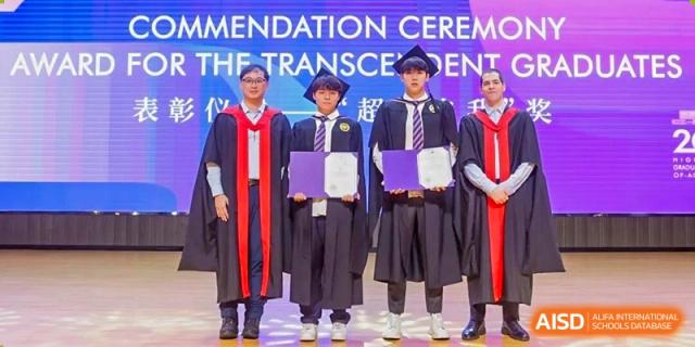 Three Cogdel Cranleigh School Changsha students in graduation robes and caps standing on stage holding certificates during a commencement ceremony.