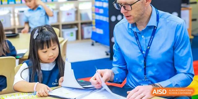 An adult or teacher at Concordia International School Shanghai going over papers and providing feedback to a student.