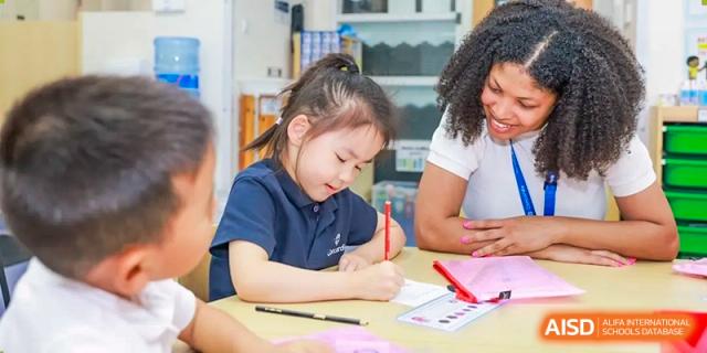 A young female student from Concordia International School Shanghai focused on writing at a desk during a class activity.