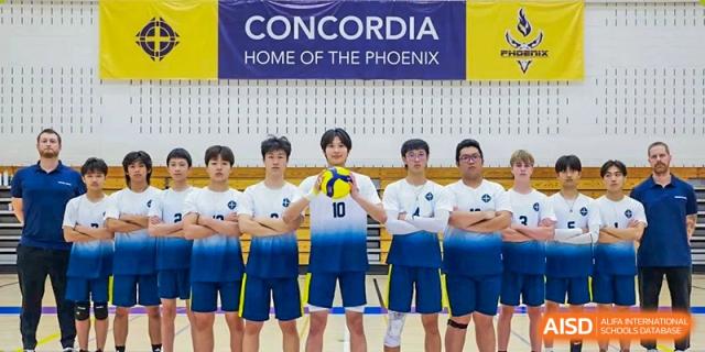 The Concordia International School Shanghai boys' volleyball team posing for a group picture beneath a banner that reads "CONCORDIA HOME OF THE PHOENIX."