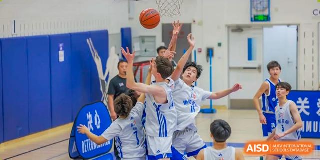 Concordia International School Shanghai students jumping to contest a basketball during a high-action game.