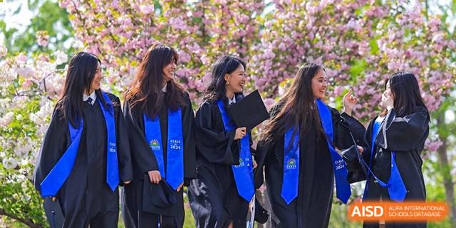 DAYSTAR ACADEMY female graduates in caps and gowns walking outside and smiling.
