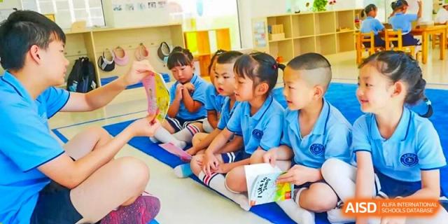 A group of young DAYSTAR ACADEMY students sitting on the floor and looking forward during a class activity.