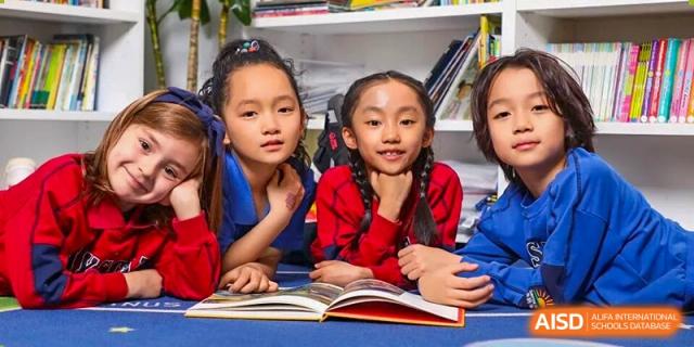 Two DAYSTAR ACADEMY female students with braided hair looking up from a book and smiling.
