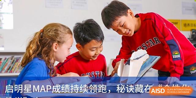 Two young DAYSTAR ACADEMY students looking intently at a tablet or screen together.