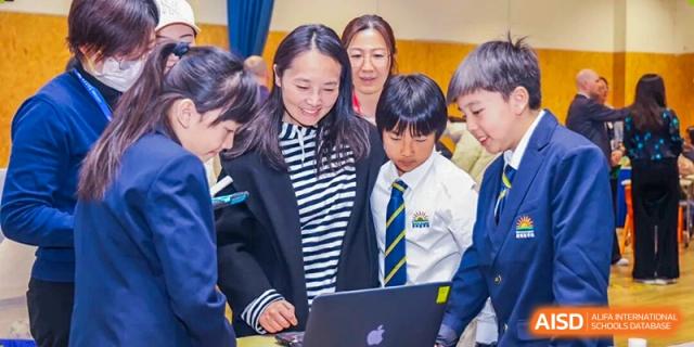 A group of DAYSTAR ACADEMY students and a teacher looking at a laptop together during a technology lesson.