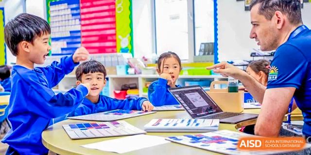 A young female student is looking up while working on an assignment with colorful art materials and a digital tablet on her desk at DAYSTAR ACADEMY.