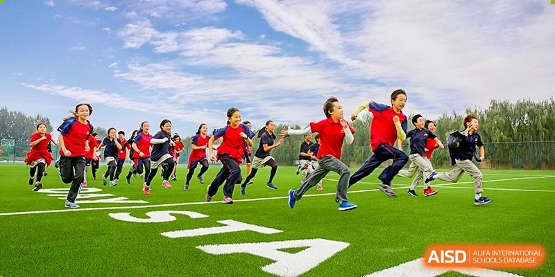 Students running on a green sports field during a physical education or sports day event at DAYSTAR ACADEMY.