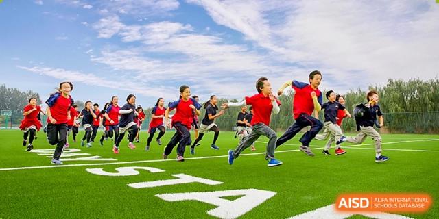 Students running on a green sports field during a physical education or sports day event at DAYSTAR ACADEMY.