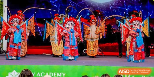 A person in a colorful traditional Chinese opera costume performing on stage at DAYSTAR ACADEMY.