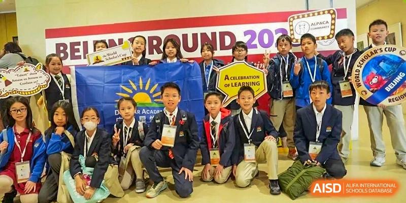A group of DAYSTAR ACADEMY students in school blazers kneeling in front of a banner promoting learning.