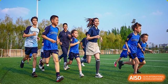 A group of DAYSTAR ACADEMY students running on a sports field during a physical activity or competition.