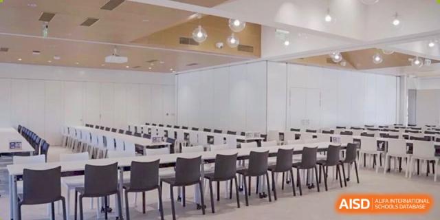 An image showing the modern, bright interior of a large meeting or multi-purpose room set up with rows of tables and chairs at DAYSTAR ACADEMY.
