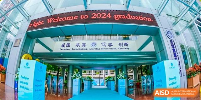 School building entrance with a red banner that reads "Welcome to 2024 Graduation" and a blue carpet leading to the door, Fuyuan British American School.