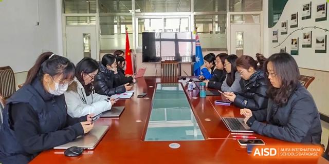 Students are seated around a long conference table during a meeting or formal discussion at Guokai International School of Qingdao.