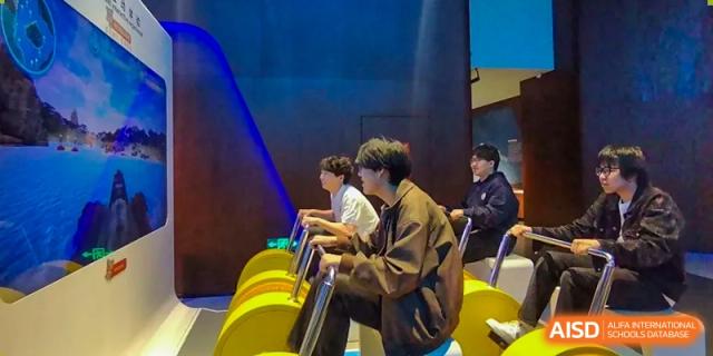 A student in a brown jacket plays a large yellow musical instrument, possibly a xylophone, during an activity at Guokai International School of Qingdao.