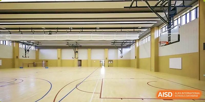 The brightly lit, polished wood floor of the empty indoor gymnasium or sports hall at Harrow Lide High School Nanning.