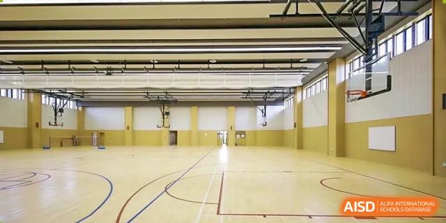 The brightly lit, polished wood floor of the empty indoor gymnasium or sports hall at Harrow Lide High School Nanning.