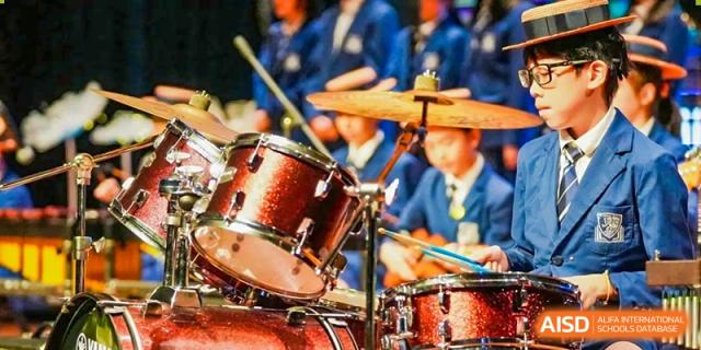Close-up of a drummer playing a drum set during a band performance at Harrow Lide High School Nanning. Highlights music and artistic education.