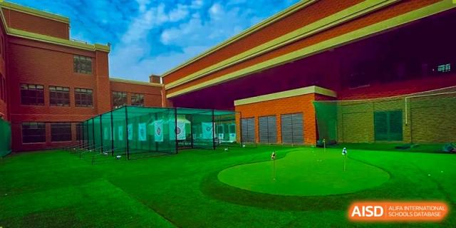 The beautifully maintained outdoor putting green and golf practice area at Harrow Lide High School Nanning. Features red brick school buildings.