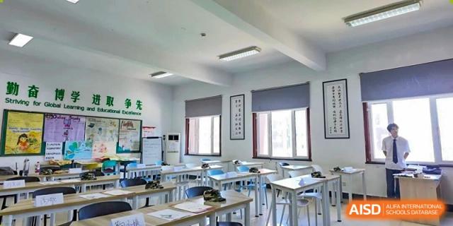 The interior of an empty classroom with rows of desks and chairs, illuminated by daylight at Maple Leaf International School-Zhenjiang.