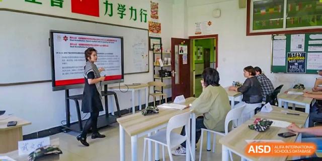 An adult sitting at a desk and working with paperwork in an office or administrative area at Maple Leaf International School-Zhenjiang.