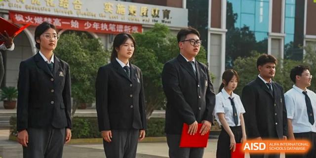 A male and a female student in formal dark uniforms standing with an adult at Maple Leaf International School-Zhenjiang.