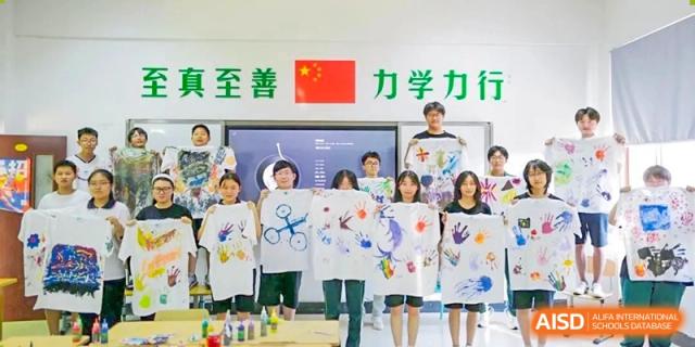 A group of young students holding a large banner they painted with the Chinese flag and text at Maple Leaf International School-Zhenjiang.