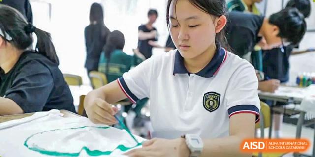 A female student focusing on an art or crafts project at a table in a bright room at Maple Leaf International School-Zhenjiang.