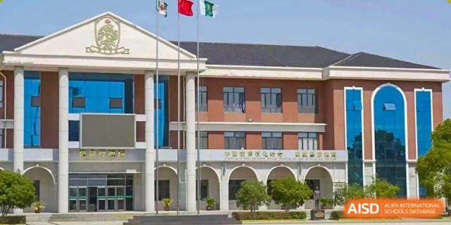 The colonial-style exterior facade of a school building with columns and flags flying on the campus of Maple Leaf International School-Zhenjiang.
